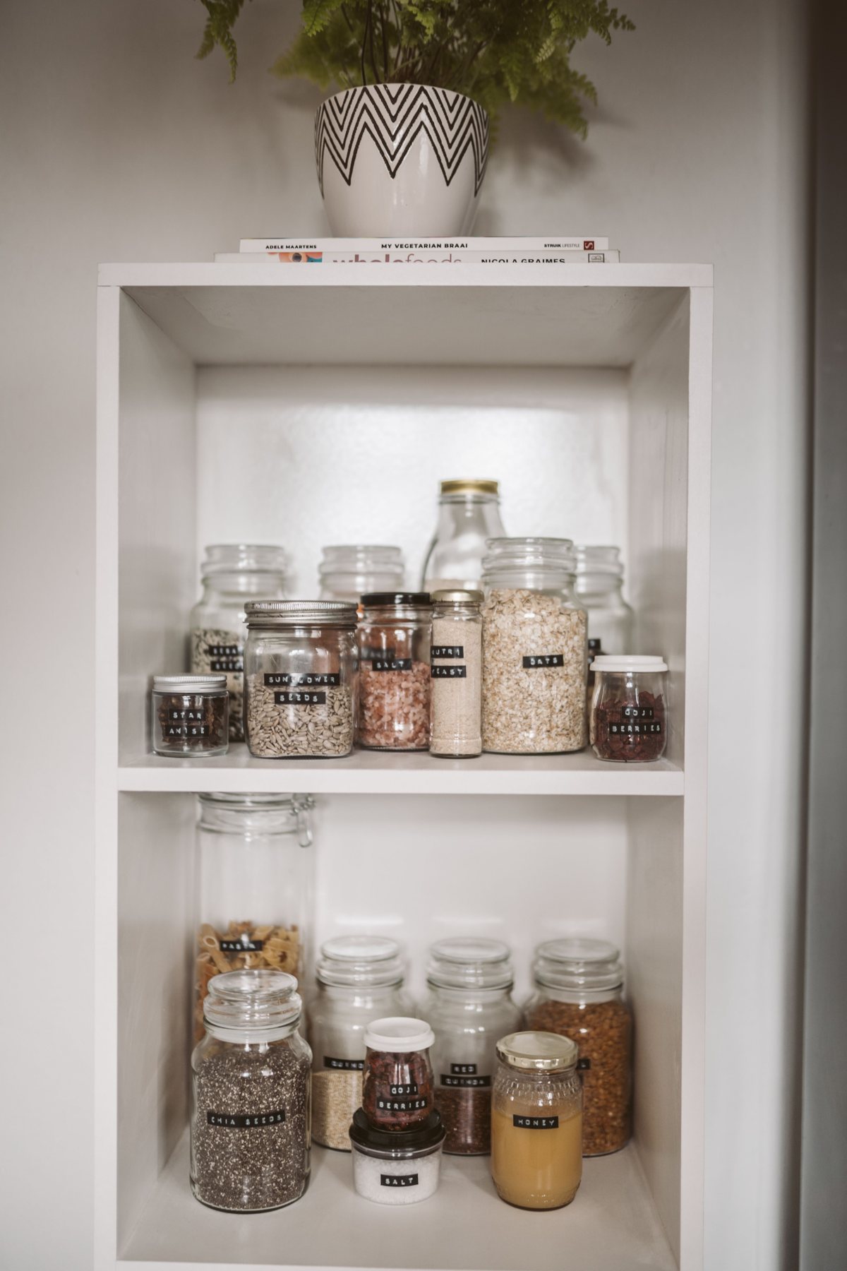 Glass jars containing grains on pantry shelves